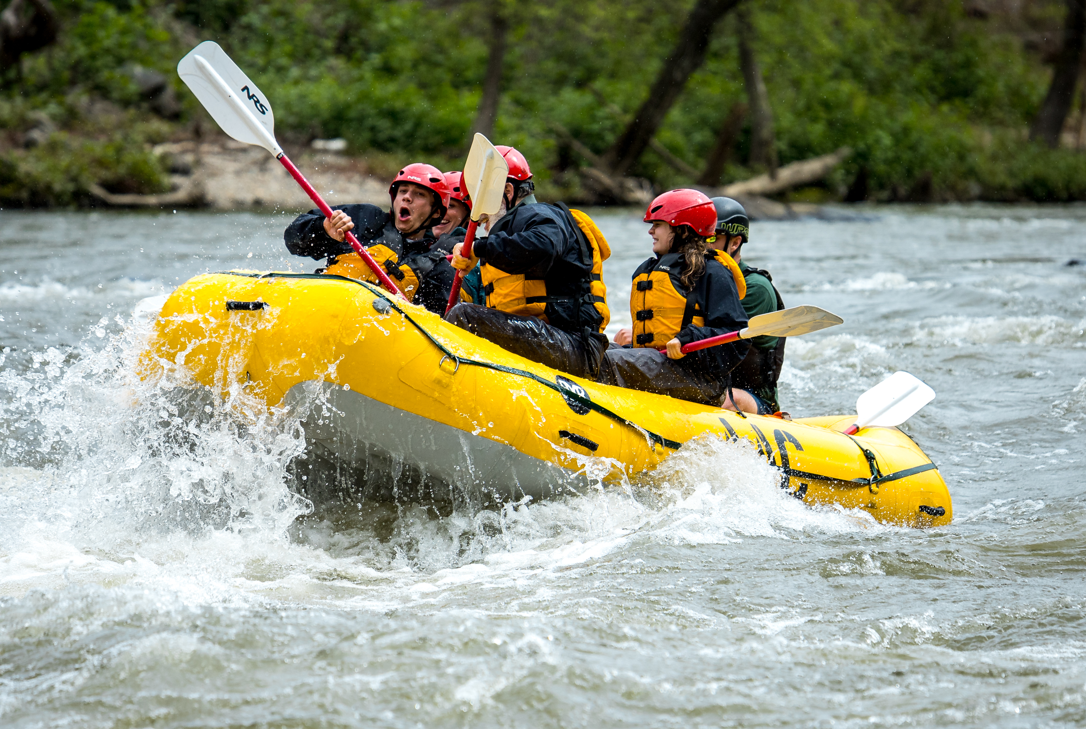 Paddlers punching through whitewater in a yellow raft